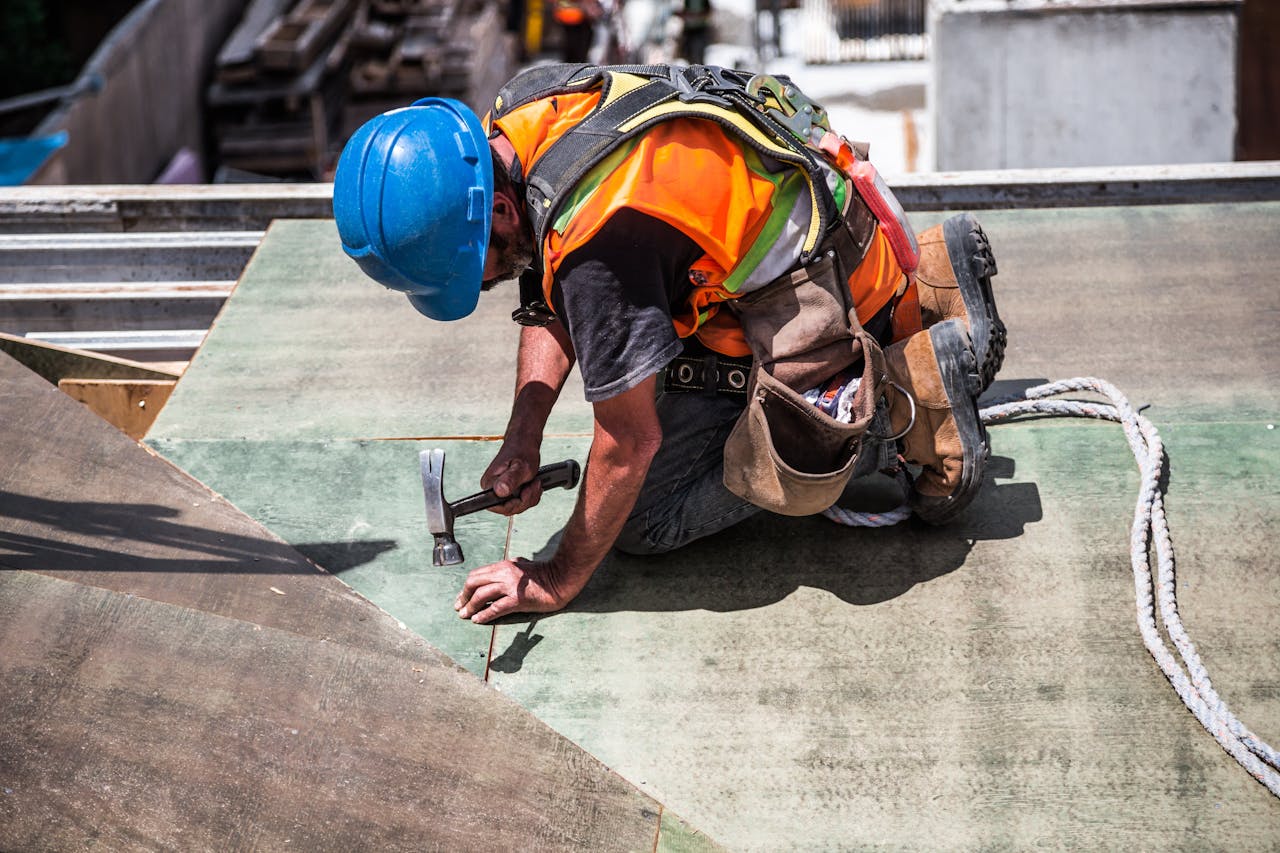 our-experience A skilled construction worker in protective gear hammering a rooftop panel.